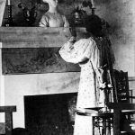 Marie Krøyer stående ved kaminen i dagligstuen
