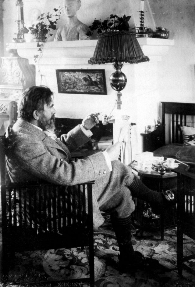 En ældet P.S. Krøyer med cigar, læsende i dagligstuen